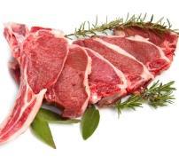 Freshly cut lamb chops arranged with herbs and green leaves